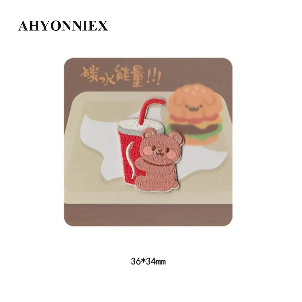 An embroidered iron-on patch featuring a cute brown bear holding a cup, with Japanese text above it.
