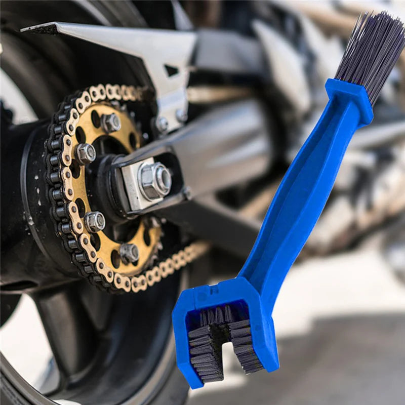 A blue universal chain cleaning brush with bristles is shown next to a motorcycle chain.