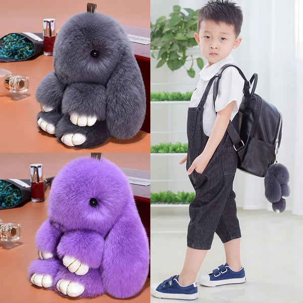 Un niño pequeño sostiene un llavero de conejo de peluche gris oscuro y uno de peluche morado.