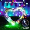 A heart-shaped flexible silver wire light display glowing brightly on green grass.
