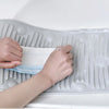 Hands are using a foldable silicone washboard with suction cups to clean or scrub a surface.