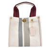 A canvas crossbody tote bag with a light beige background and vertical gray stripes, featuring a maroon strap and gold hardwa