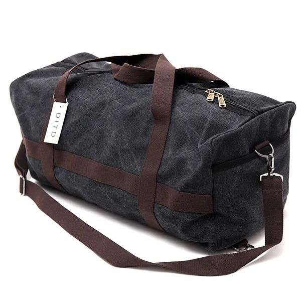 Maleta de viaje tipo duffel de lona gris oscura con correas y cremalleras marrones.