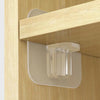 A close-up view of clear adhesive shelf support pegs mounted on a wooden cabinet shelf.