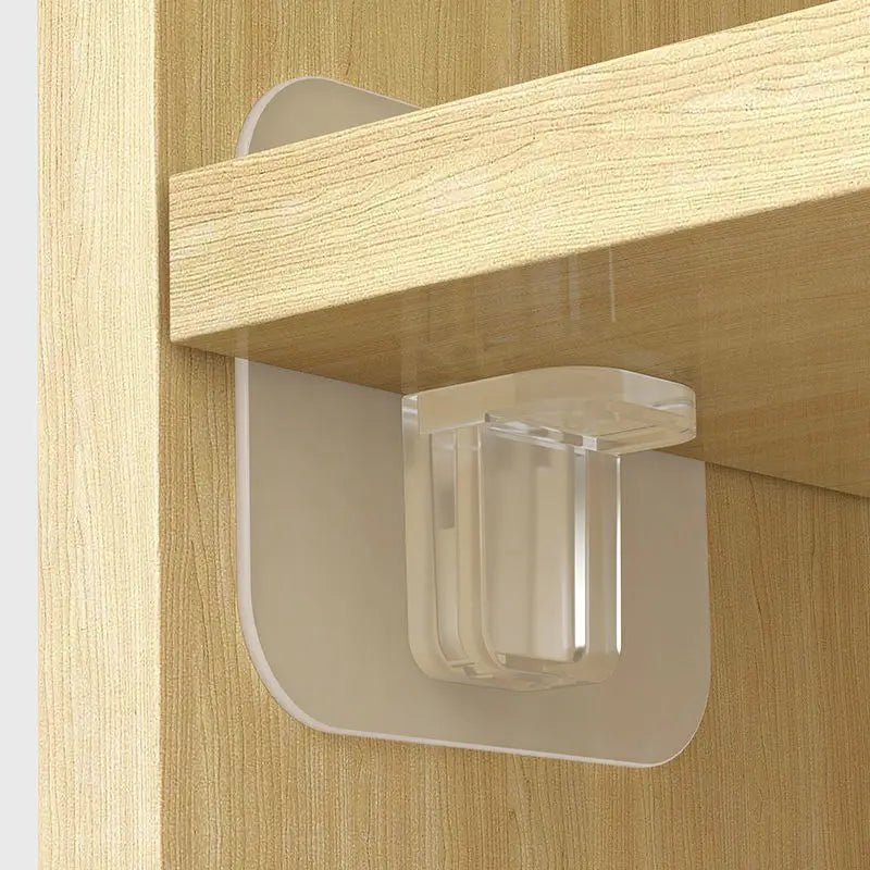 A close-up view of clear adhesive shelf support pegs mounted on a wooden cabinet shelf.