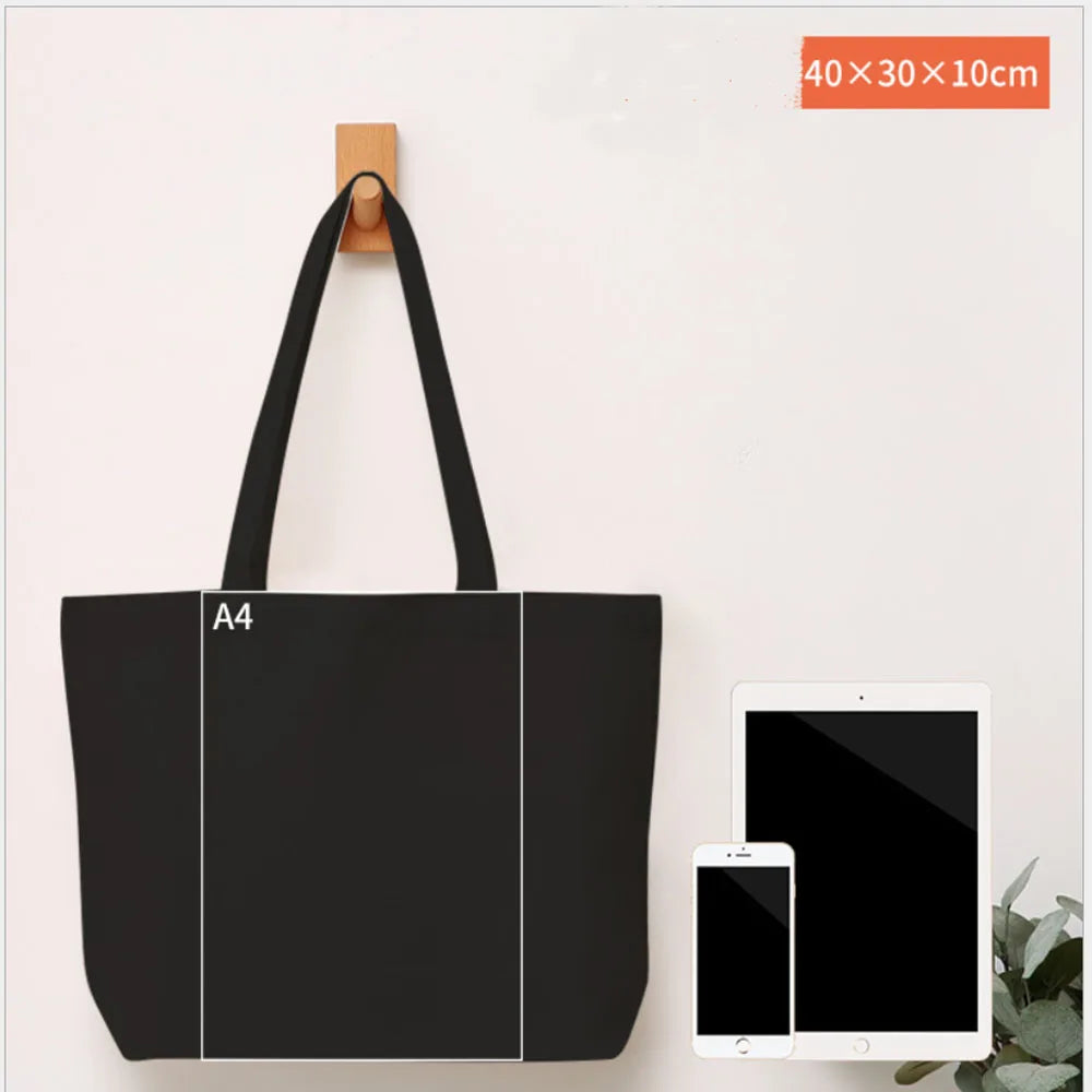 A black A4 sized canvas tote bag with a wooden hanger displayed on a white background.