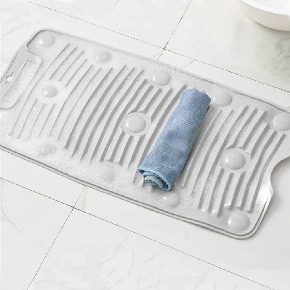 A clear silicone washboard with suction cups and a folded blue cloth placed on it.