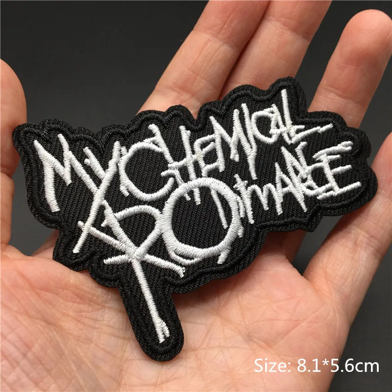 Black embroidered punk skull patches with white text on a hand