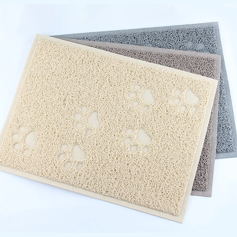 A stack of cat litter mats featuring paw print designs in beige, gray, and blue tones.