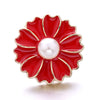 A red enamel flower button with a white pearl center and gold trim.