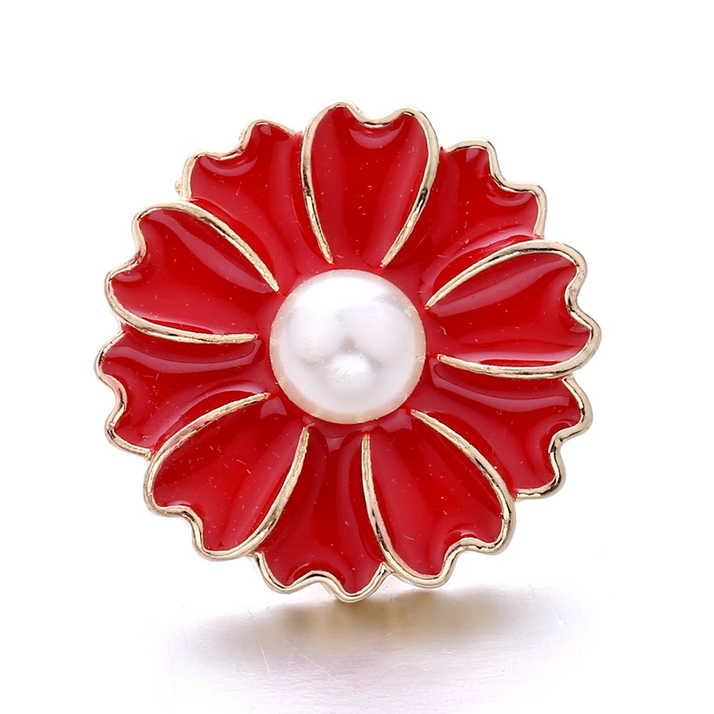 A red enamel flower button with a white pearl center and gold trim.