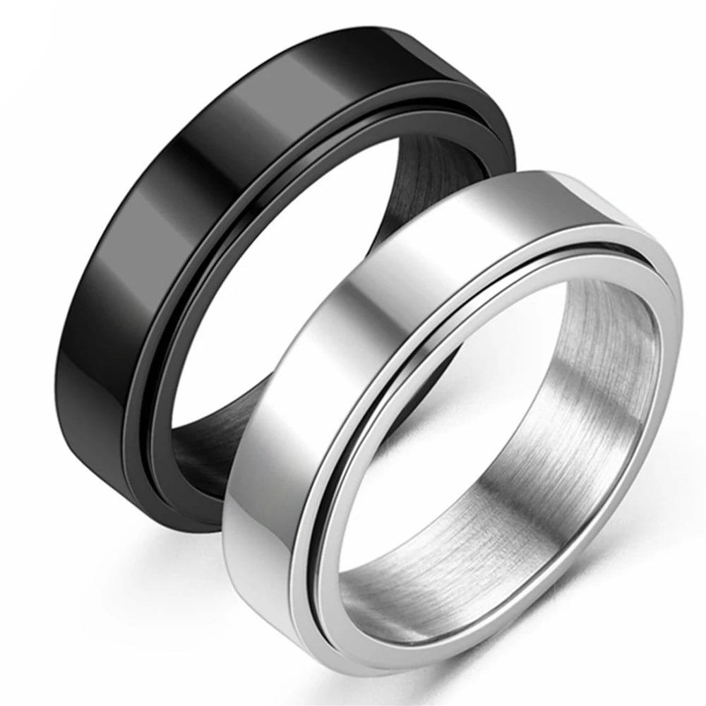 A close-up view of a silver stainless steel anxiety spinner ring with a black band lying on a white surface.