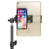 A beige iPad is mounted on an adjustable aluminum tripod stand, holding an iPhone.