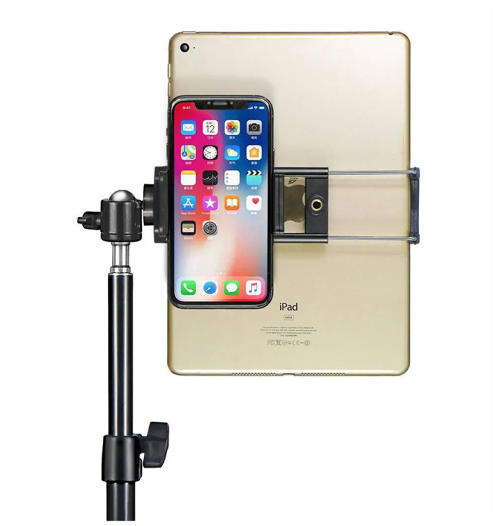 A beige iPad is mounted on an adjustable aluminum tripod stand, holding an iPhone.
