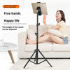 A woman is using an adjustable aluminum tripod stand to hold a tablet or phone while relaxing on a sofa.