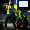 A man wearing a blue shirt and dark pants holds a yellow high-visibility safety vest while another person is visible in the b