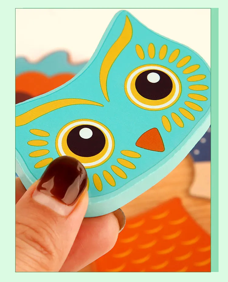 A hand holds a wooden 3D owl puzzle piece with yellow and black markings against an orange background.