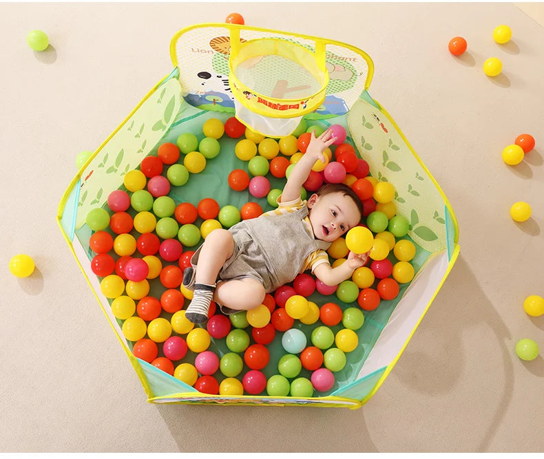 A baby is playing with colorful, ocean-themed soft play pit balls inside a yellow container.