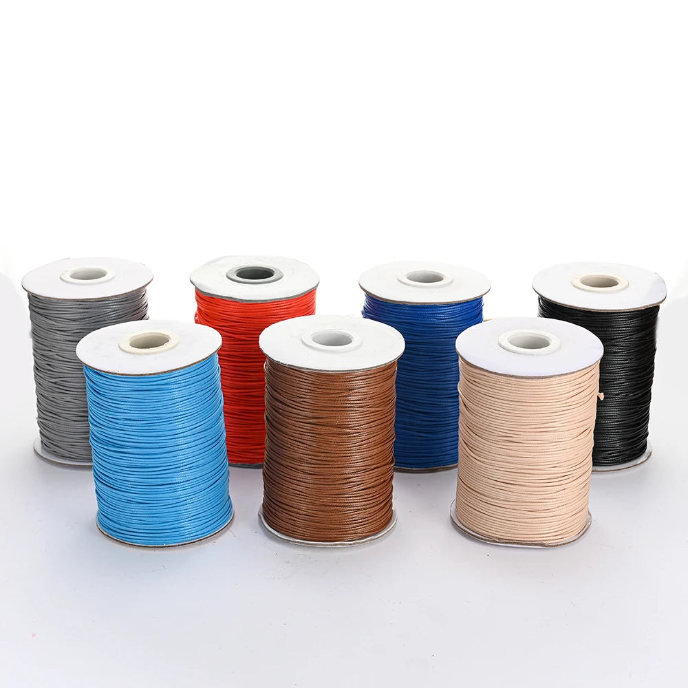 A collection of spools of colorful waxed cotton cord in various shades including gray, red, blue, and tan.