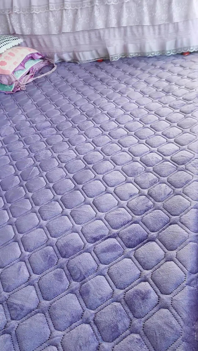 A purple quilted velvet bedspread with a diamond pattern laid out on a floor.