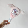 A hand holds a pink fluffy plush cover for a SEVENTEEN official light stick.