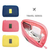 A set of three compact travel cable organizer bags in navy blue, pink, and yellow.