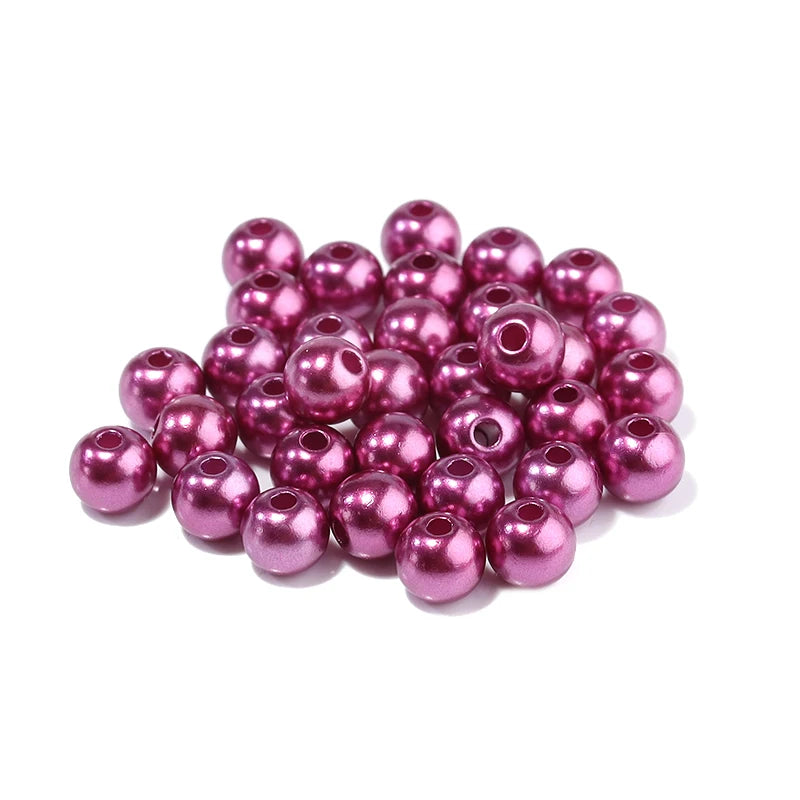 A pile of round, magenta imitation pearl beads for jewelry making.