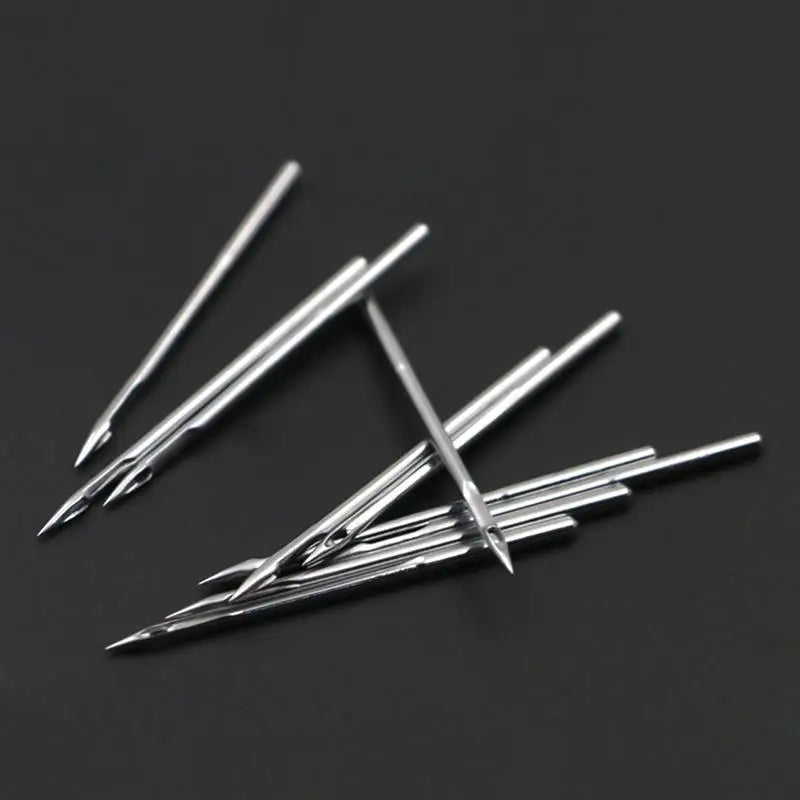 A multi-pack of sharp silver sewing machine needles laid diagonally on a dark surface.