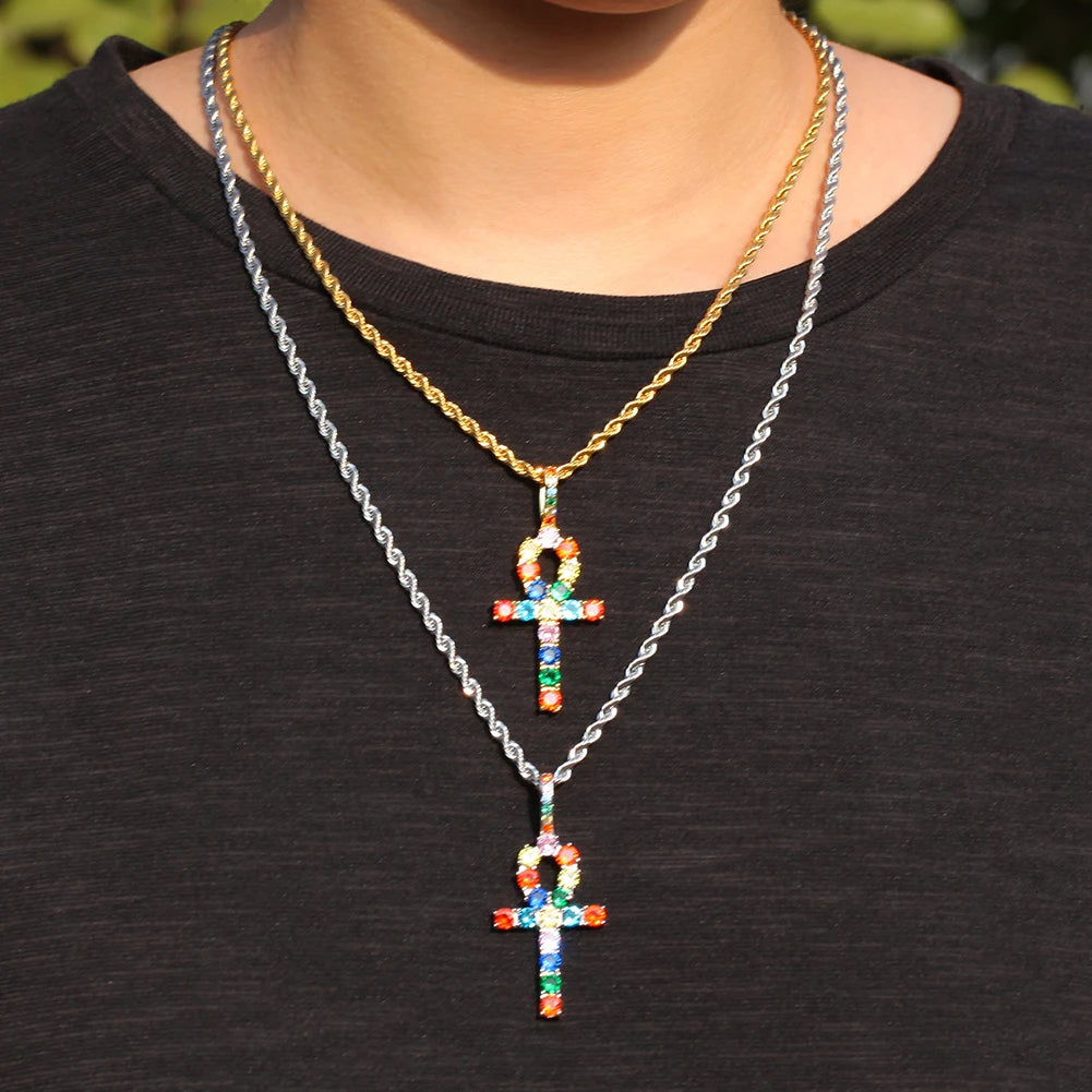 Gold and silver chain necklace with a rainbow ankh cross pendant worn against a black shirt.