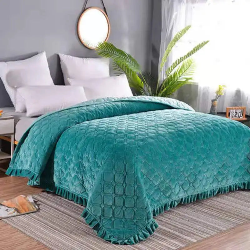 Teal quilted velvet bedspread with a diamond pattern draped over a bed.
