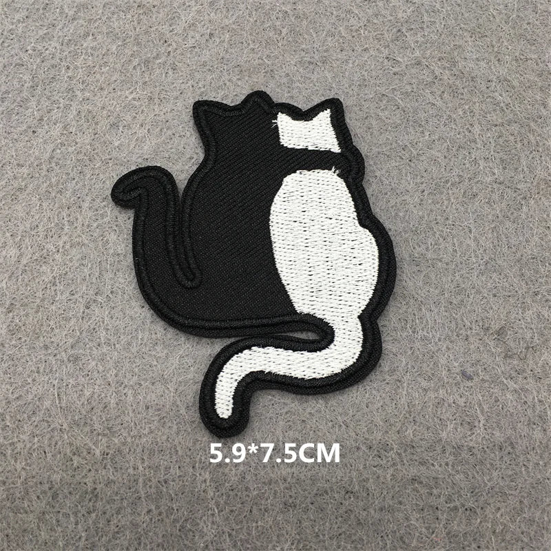 Black and white cat silhouette embroidered iron-on patch on a gray fabric.