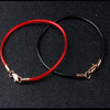 A pair of jewelry making bracelets, one red waxed cotton cord and one black cord with gold clasps.