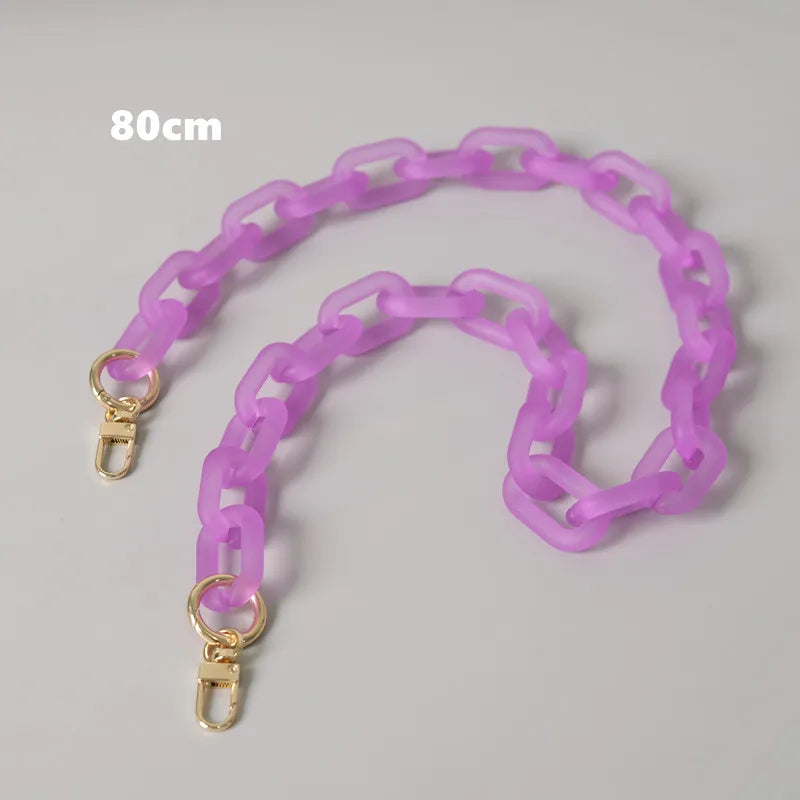 Lila Kettengurt für eine Tasche, ausgebreitet auf grauem Hintergrund.