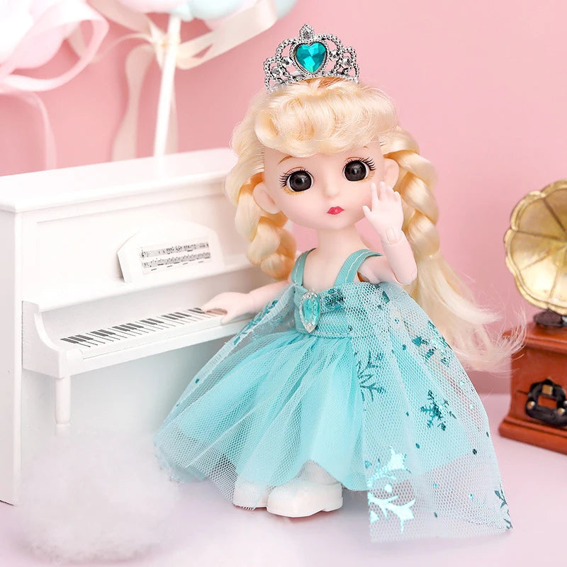 A blonde fashion doll wearing a light blue tulle dress and a sparkly crown standing next to a white piano.