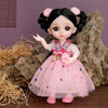 A pink fashion doll with black hair and a floral dress is displayed in a natural, rocky setting.
