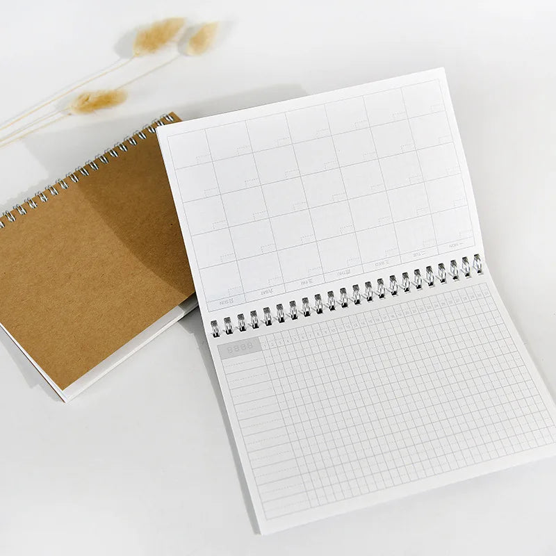 A white A5 spiral-bound monthly planner open to a blank page with grid lines.