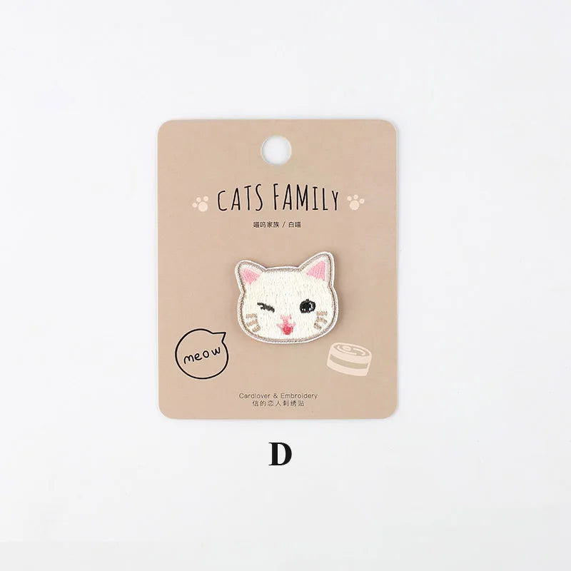 A light beige iron-on patch featuring a white embroidered cat face with pink accents.