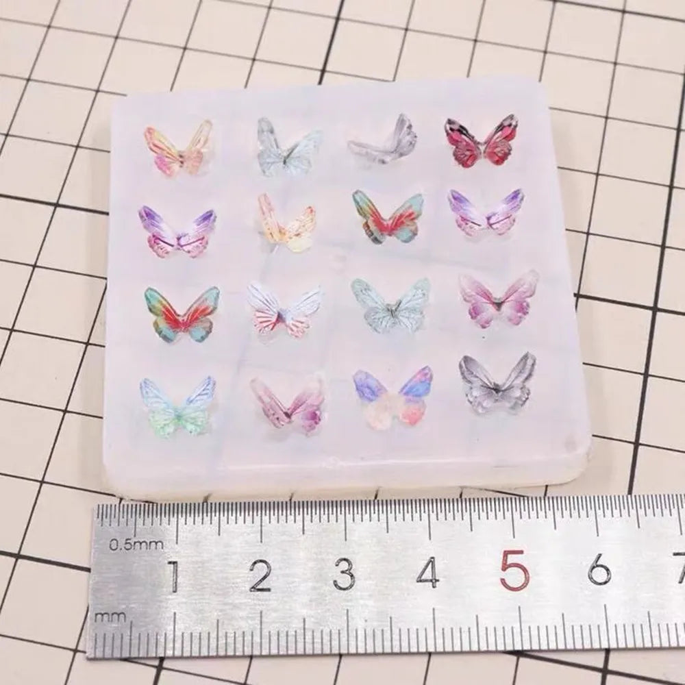 A clear silicone mold containing multiple butterfly shaped epoxy resin pieces for DIY jewelry making