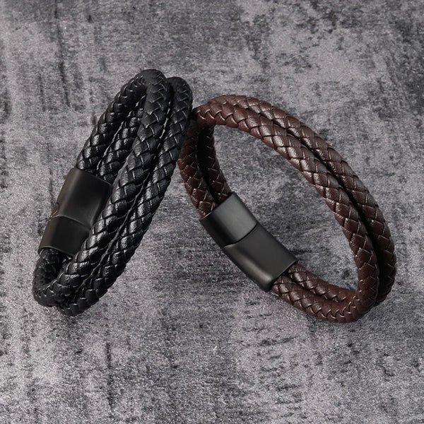 Un par de pulseras de cuero y acero inoxidable para hombre con cierres magnéticos, una negra y una marrón, sobre una superfic