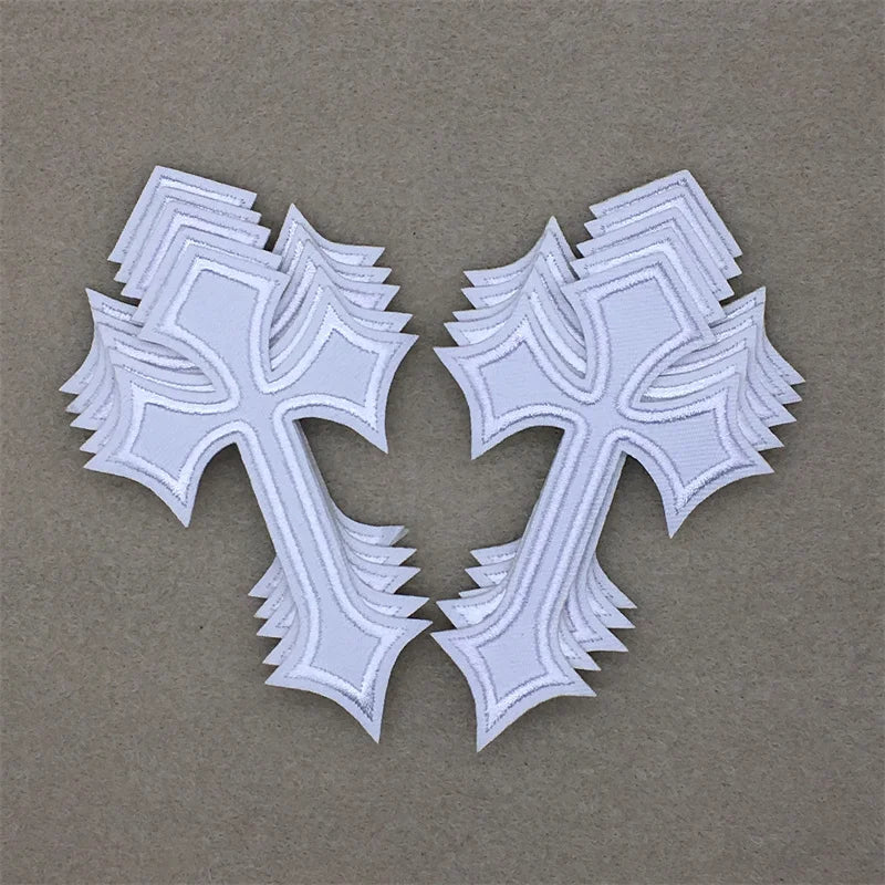 A set of ten embroidered cross iron-on patches in white on a beige background.