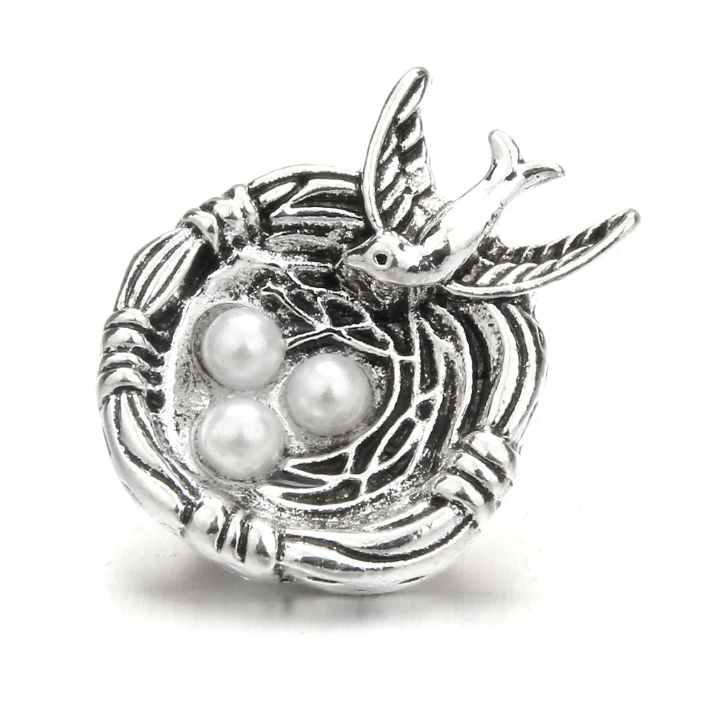 Silver metal snap buttons featuring a bird and three white pearls for jewelry making