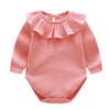 A pink ribbed cotton romper for a baby girl with a ruffled neckline.