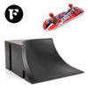 A finger skateboard featuring a red deck and black wheels, shown next to a black park ramp.