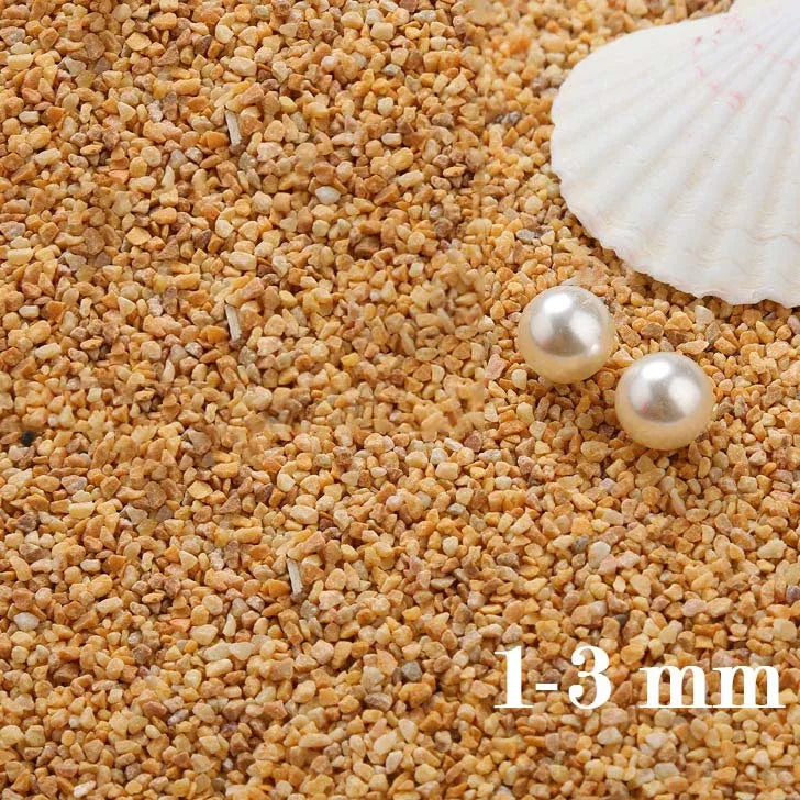 Small decorative stone pebbles measuring 1-3 mm scattered on a light background next to a seashell.