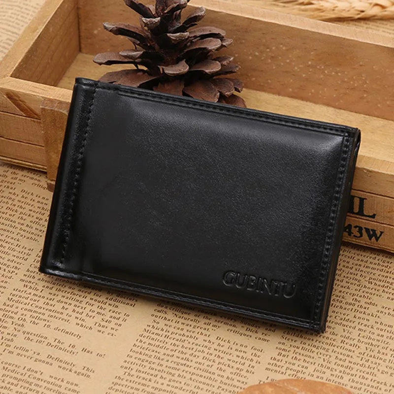 A black men's leather money clip wallet with magnetic closure resting on a wooden surface.