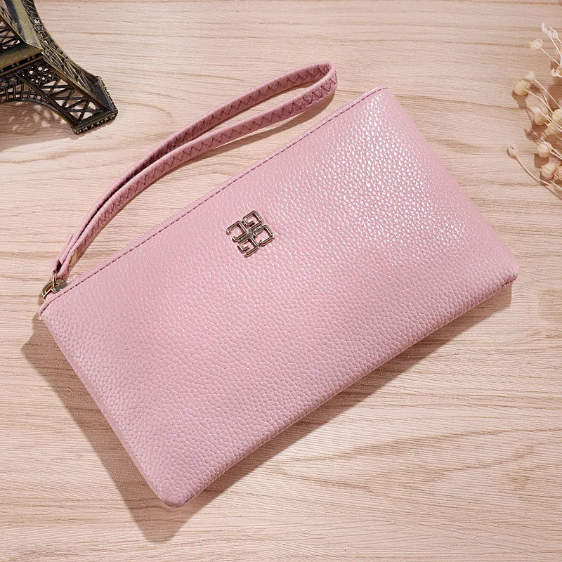 A light pink Litchi-Grain PU leather long wallet with a strap resting on a wooden surface.