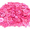 A pile of assorted pink and magenta wooden buttons for sewing and crafts.