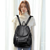 A woman wearing a black vintage faux leather backpack with multiple compartments.