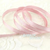 Roll of light pink satin ribbon, 1 inch wide and 25 yards, laid on white lace fabric.