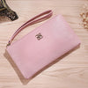 A light pink Litchi-Grain PU leather long wallet with a strap resting on a wooden surface.